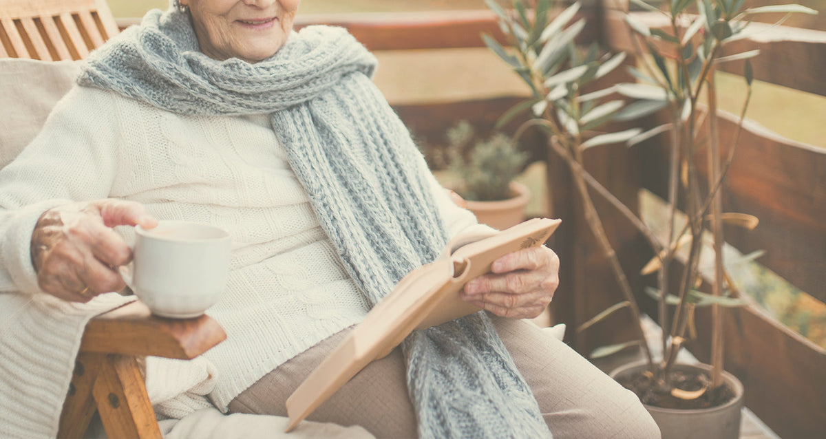 Retired woman with mug reading outside